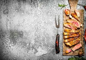 Meat grill. Cut a steak of roasted meat with spices. On rustic background. photo