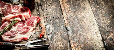 Raw meat background. Pieces of raw steak with spices and herbs. On wooden background. photo