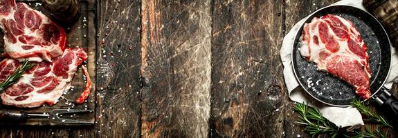 Raw meat background. Pieces of raw steak with spices and herbs. On wooden background. photo