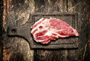 Raw meat background. A piece of raw steak on cutting Board . On wooden background. photo