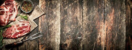 Raw meat background. Pieces of raw steak with spices and herbs. On wooden background. photo