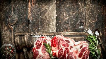 Raw meat background. Pieces of raw steak with spices and herbs. On wooden background. photo