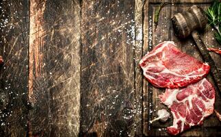 Raw meat background. Pieces of raw steak with spices and herbs. On wooden background. photo