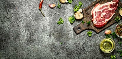 Raw meat background. A piece of Raw pork chops with fragrant spices and fresh herbs. On rustic background. photo