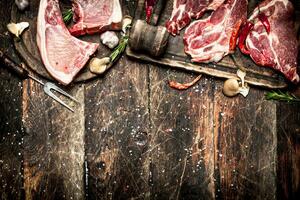 Raw meat background. Raw pork chop with a variety of herbs and spices. photo