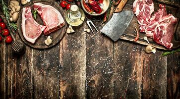 Raw meat background. Raw pork chop with a variety of herbs and spices. photo