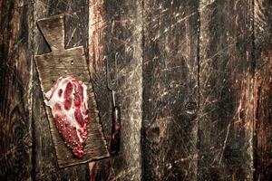 Raw meat background. A piece of raw steak on cutting Board . On wooden background. photo