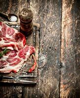 Raw meat background. Pieces of raw steak with spices and herbs. On wooden background. photo