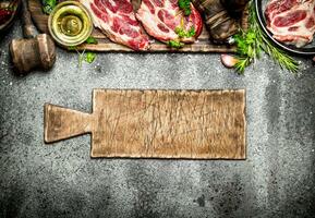 Raw meat background. Raw steak with herbs and spices on the old Board. On rustic background. photo