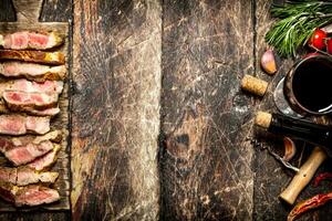 Meat grill. Pieces of pork grilled with spices and red wine. On the old wooden table. photo