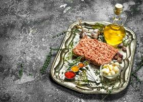 Fresh minced meat with spices and herbs on a steel tray. photo