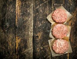 Raw burger from beef. On wooden background. photo