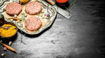 Raw burger with garlic and spices on a steel tray. photo