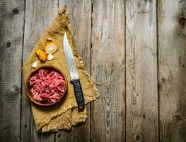 crudo suelo carne de vaca con un Carnicero cuchillo y un cebolla. foto