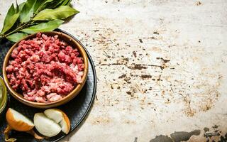 Minced meat in a wooden bowl with spices and oil. photo