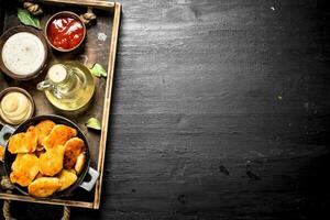 Nuggets from chicken meat with sauces on a tray. photo