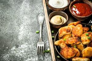 Chicken nuggets with different sauces on an old tray. photo