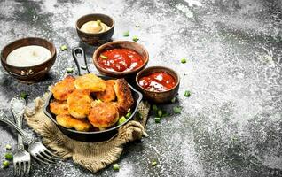 Chicken nuggets in a pan with different sauces. photo