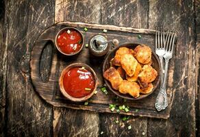 Chicken nuggets in a bowl with tomato sauce. photo