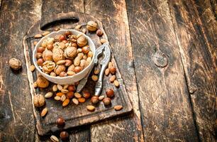 Nuts with Nutcracker in a bowl on the old Board. photo