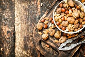 Nuts with Nutcracker in a bowl on the old Board. photo