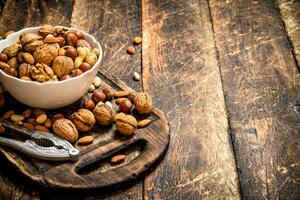 Nuts with Nutcracker in a bowl on the old Board. photo