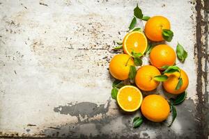 Fresh oranges with leaves. On rustic background. photo