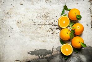 Fresh oranges with leaves. On rustic background. photo