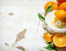 Squeezing juice from fresh oranges . On rustic background. photo