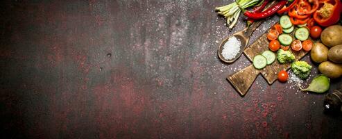 Organic Food. Sliced fresh vegetables on the old Board. On rustic background. photo