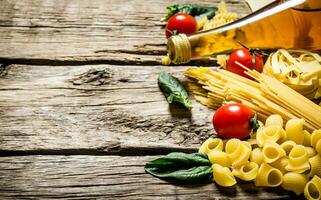 Mixed dry pasta and spaghetti, with tomatoes, herbs and olive oil. photo