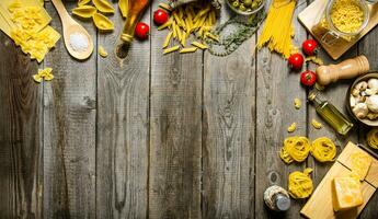 Pasta background. Several types of dry pasta with vegetables, cheese and herbs. photo