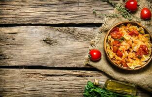 Cooked pasta with tomato sauce and herbs on the fabric. photo