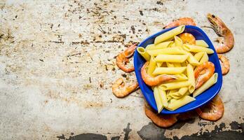 Pasta with shrimps in a plate. On rustic background. photo