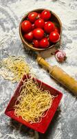 Noodles with tomatoes and a rolling pin. photo