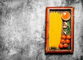 Pasta background. Spaghetti with sauce and tomatoes in the old tray. photo