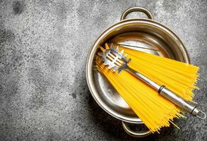 Pasta background. Spaghetti in a pot with a ladle. photo