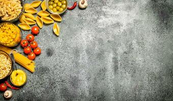 Pasta background. Various pasta with spices and vegetables. photo