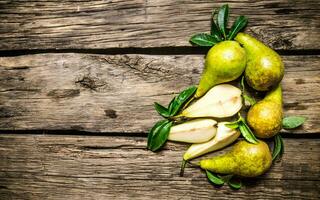 Fresh pears with leaves. On wooden background. photo