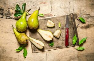 Sliced pears on old chopping board with leaves . photo