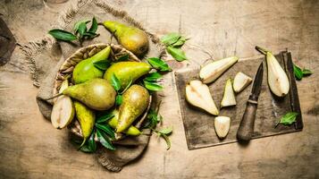 Cut fresh pears on old cutting Board, with a basket full of pears. photo