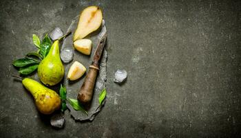 Sliced pears with leaves, ice and knife on a stone stand. photo