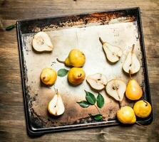 Ripe pears on a baking tray with green leaves. photo