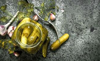 Marinated cucumbers with garlic, spices and herbs in glass jar. photo