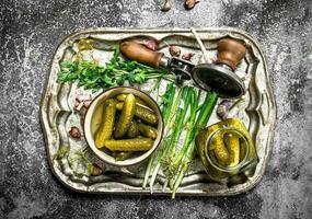 Pickled cucumbers with herbs and spices on a steel tray. photo