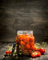 en escabeche Tomates con hierbas y especias en frasco. foto