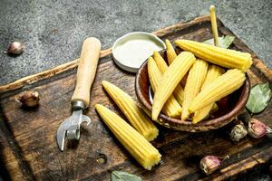 Pickled corn in a jar on a cutting board. photo