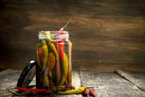 Pickled hot chili peppers in glass jar. photo