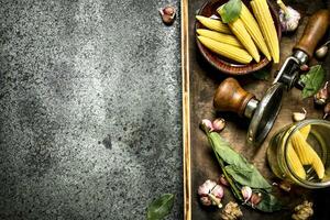 Pickled corn with spices and seamer on a tray. photo