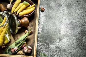 Pickled corn with spices and seamer on a tray. photo